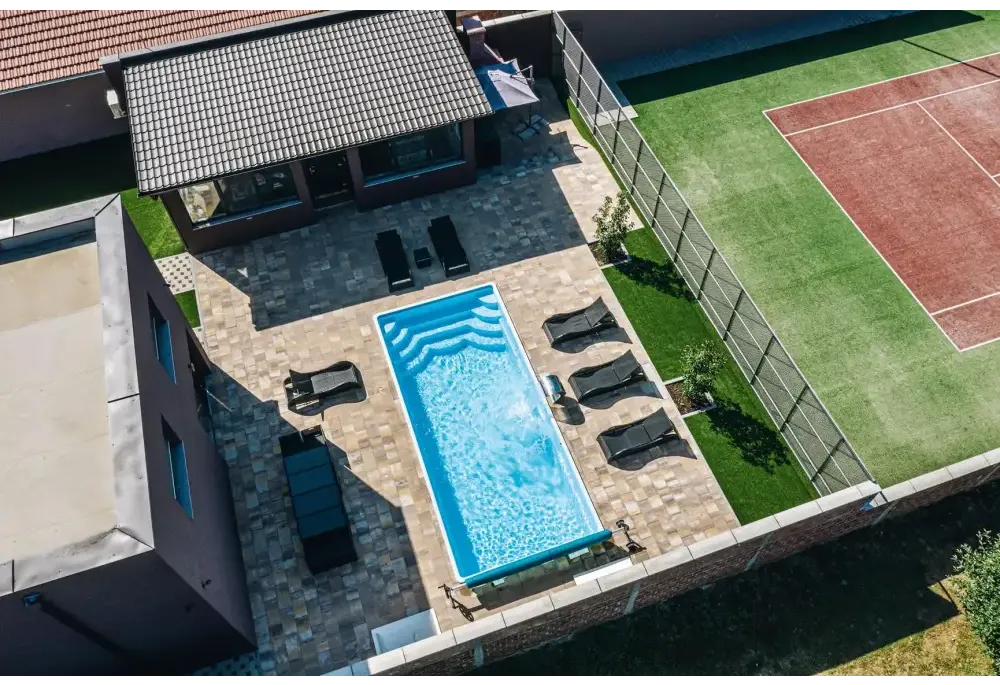 Blå rektangulär glasfiberpool Aruba med kaklade kanter och vattenrullningar