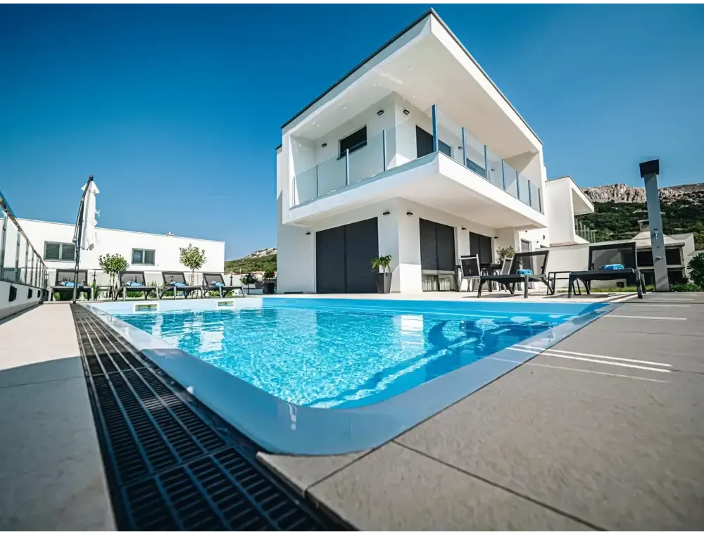 Modern blå rektangulär glasfiberpool Aruba med kaklad omgivning och vit villa