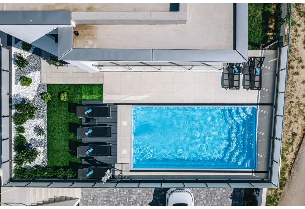 Blå rektangulär glasfiberpool Aruba med kaklad omgivning och klart vatten