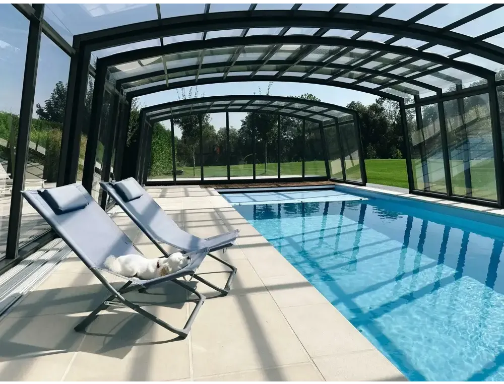 Ljusblå tygfåtölj med metallram vid Bahama trädgårdspool med transparent pooltak
