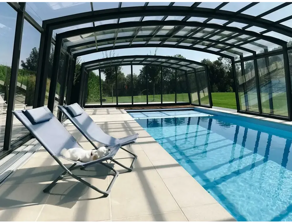 Ljusblå tygfåtölj med metallram vid Bahama trädgårdspool med transparent pooltak