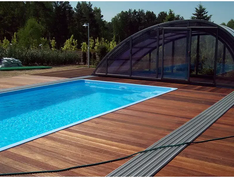 Rektangulär glasfiberpool Jamaika 25x3 75x1 50m med klart blått vatten, trädeck och valvformad glastäckning