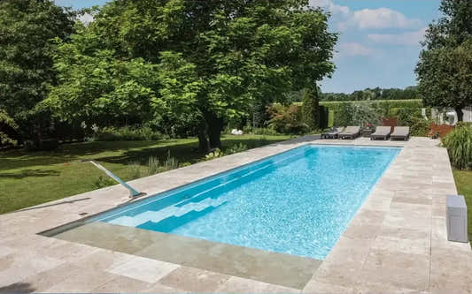 Leisurepools Definitive -allas – korkea vedenpinta, suorakulmainen allas, kirkas sininen vesi, beiget kivilaatat