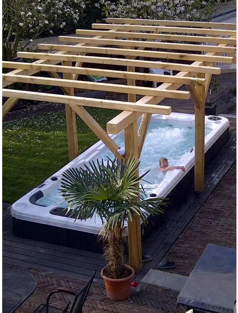 Vit och svart PassionSpa Aquatic 2 Swim Spa med bubblande vatten under pergola