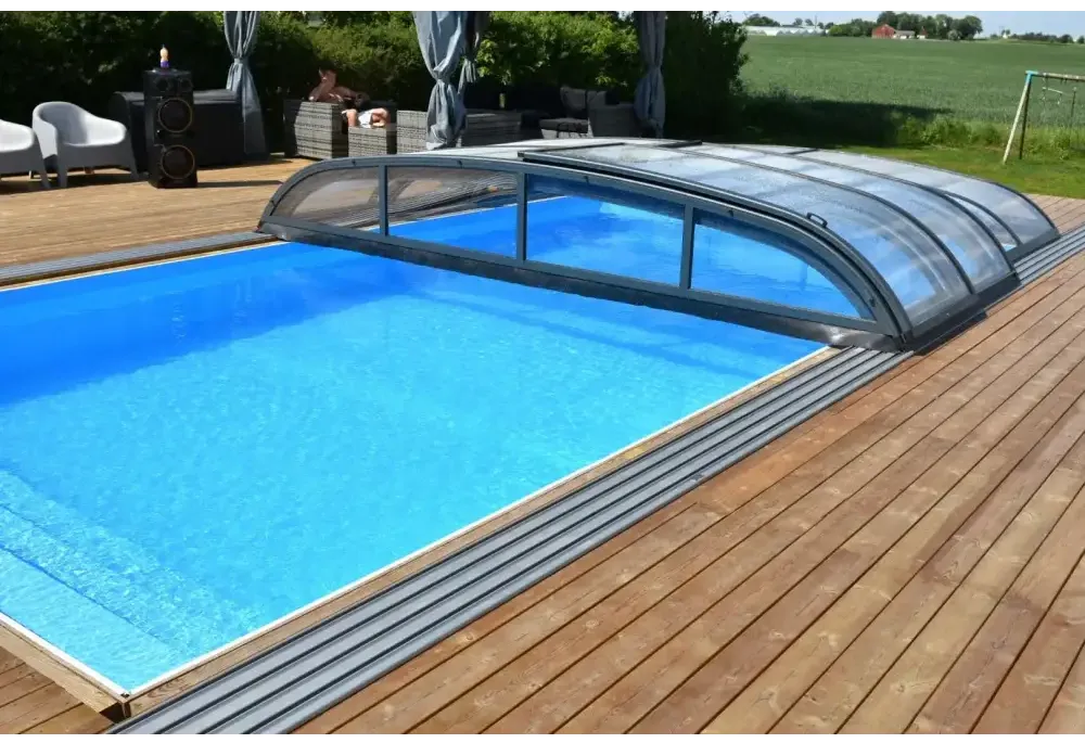 Blå inground pool med Pooltak Nivo Kit 1060B bågad täckning på trädeck
