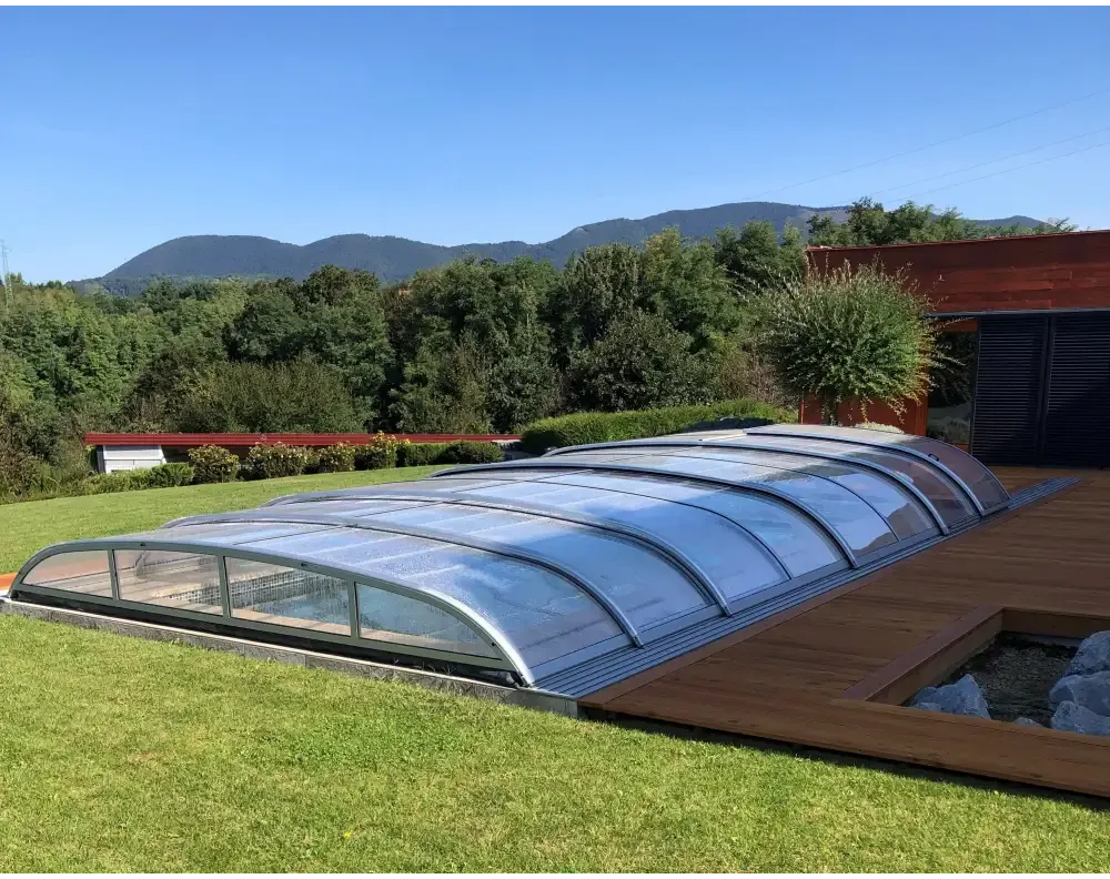 Curved transparent polycarbonate roof with metallic frame over outdoor pool, Pooltak NIVO KIT 750B