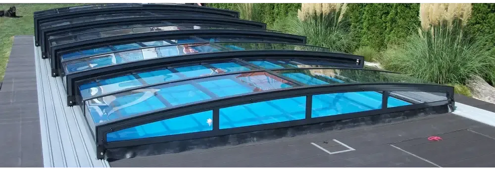 Pooltak special med böjd glasdesign och svart ram över blå poolvatten