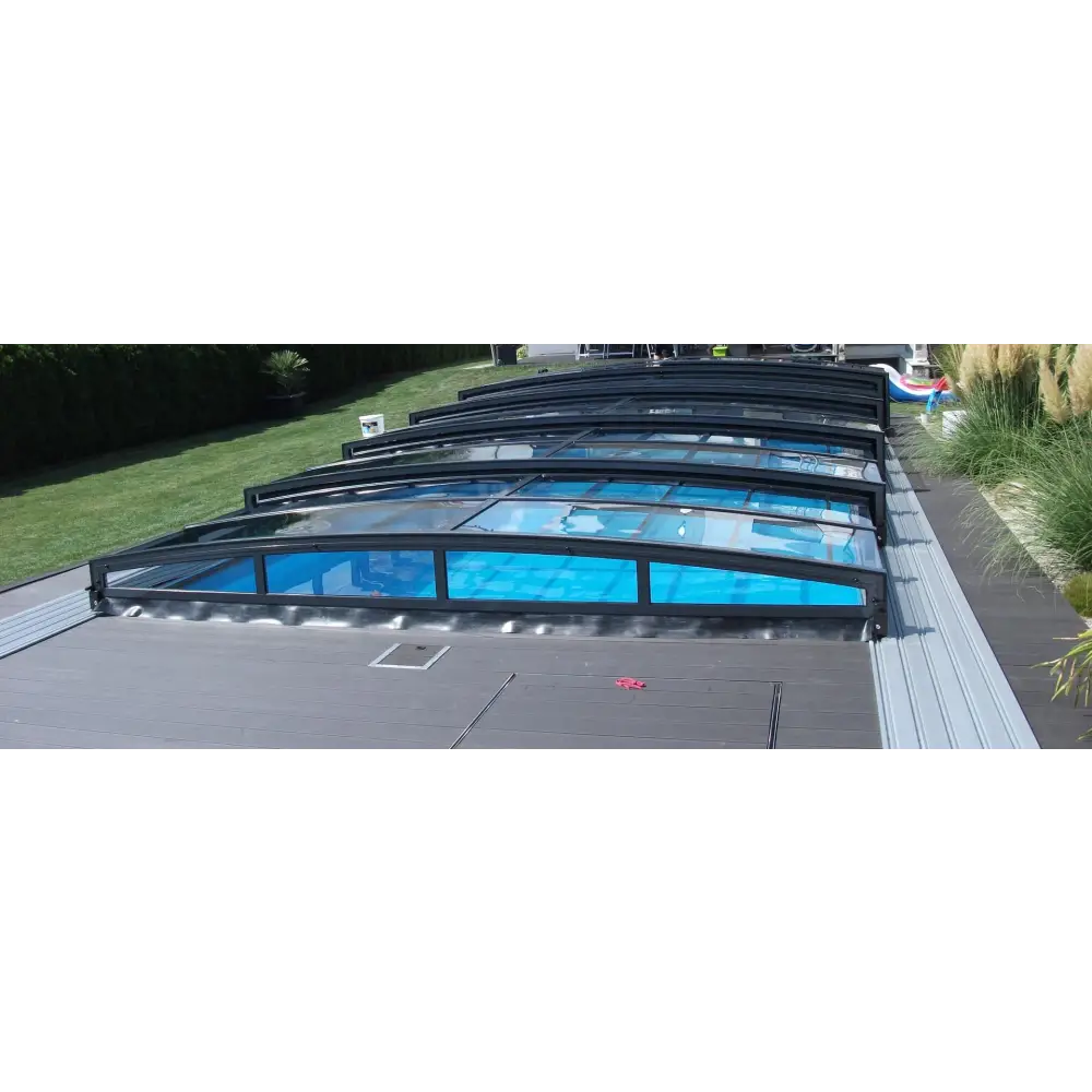Pooltaket Special med RAL7016 antracit profiler, svart ramad kurvad glaspooltäckning med transparenta paneler som visar blått vatten under